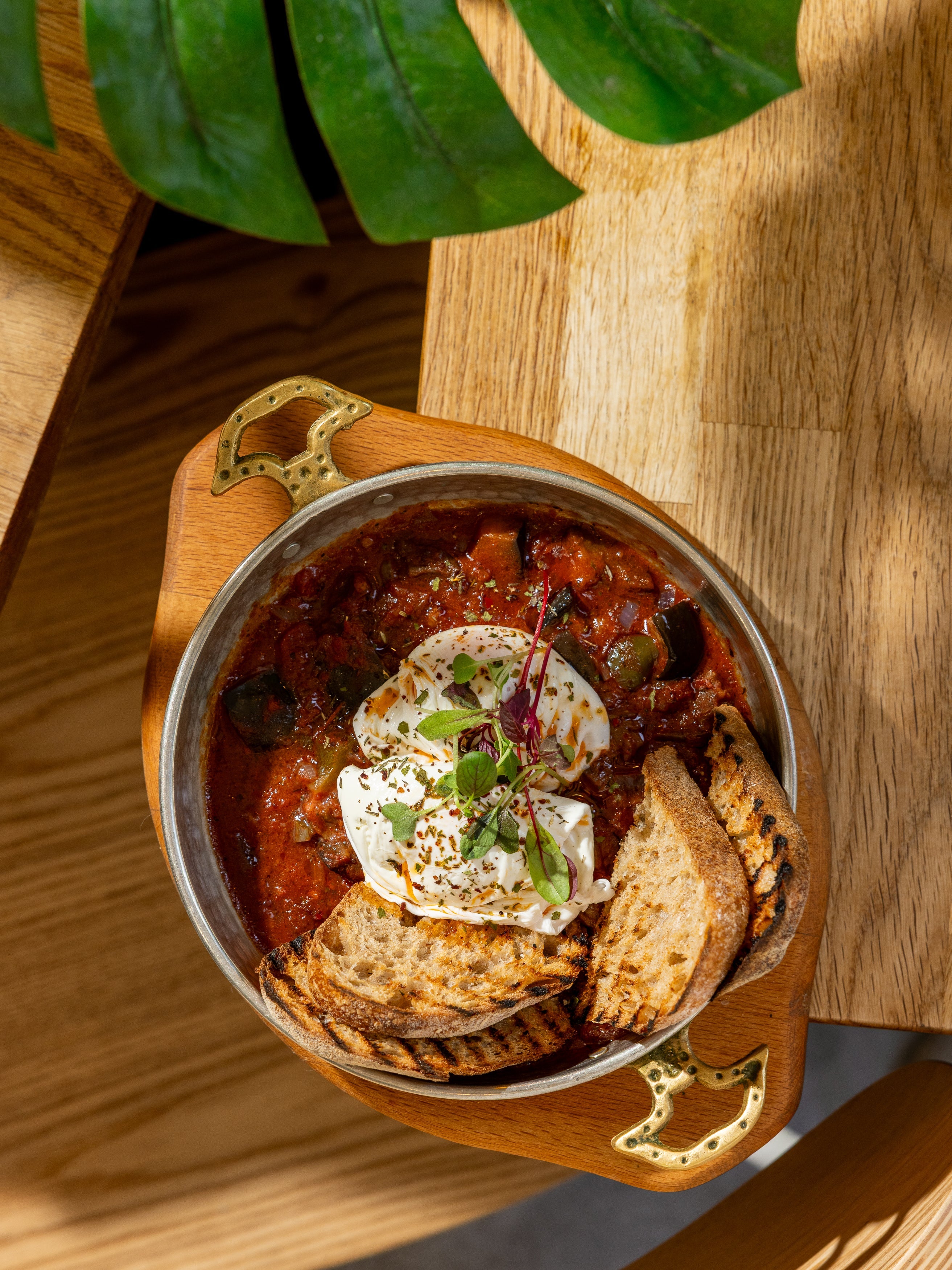 Shakshuka baked in a copper pan with poached eggs and grilled sourdough at Kybelle Café, Shoreditch
