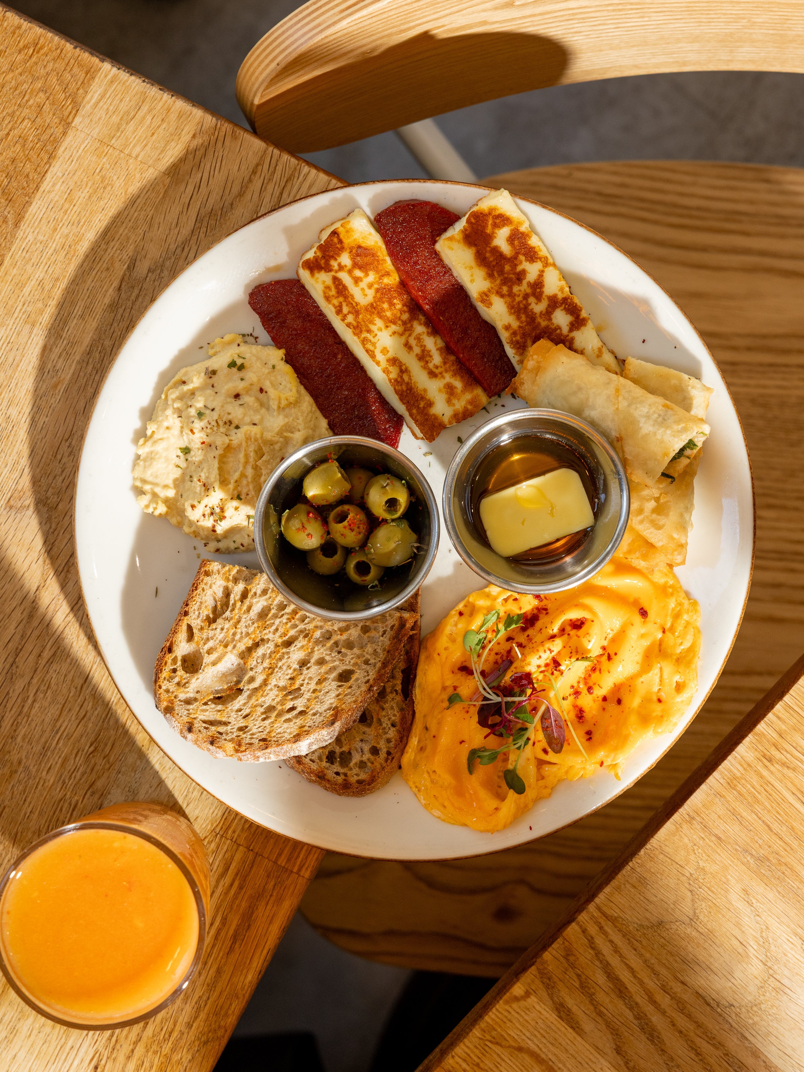 Halal-friendly Mediterranean breakfast plate with grilled halloumi, sujuk, börek and olives at Kybelle Café, Shoreditch